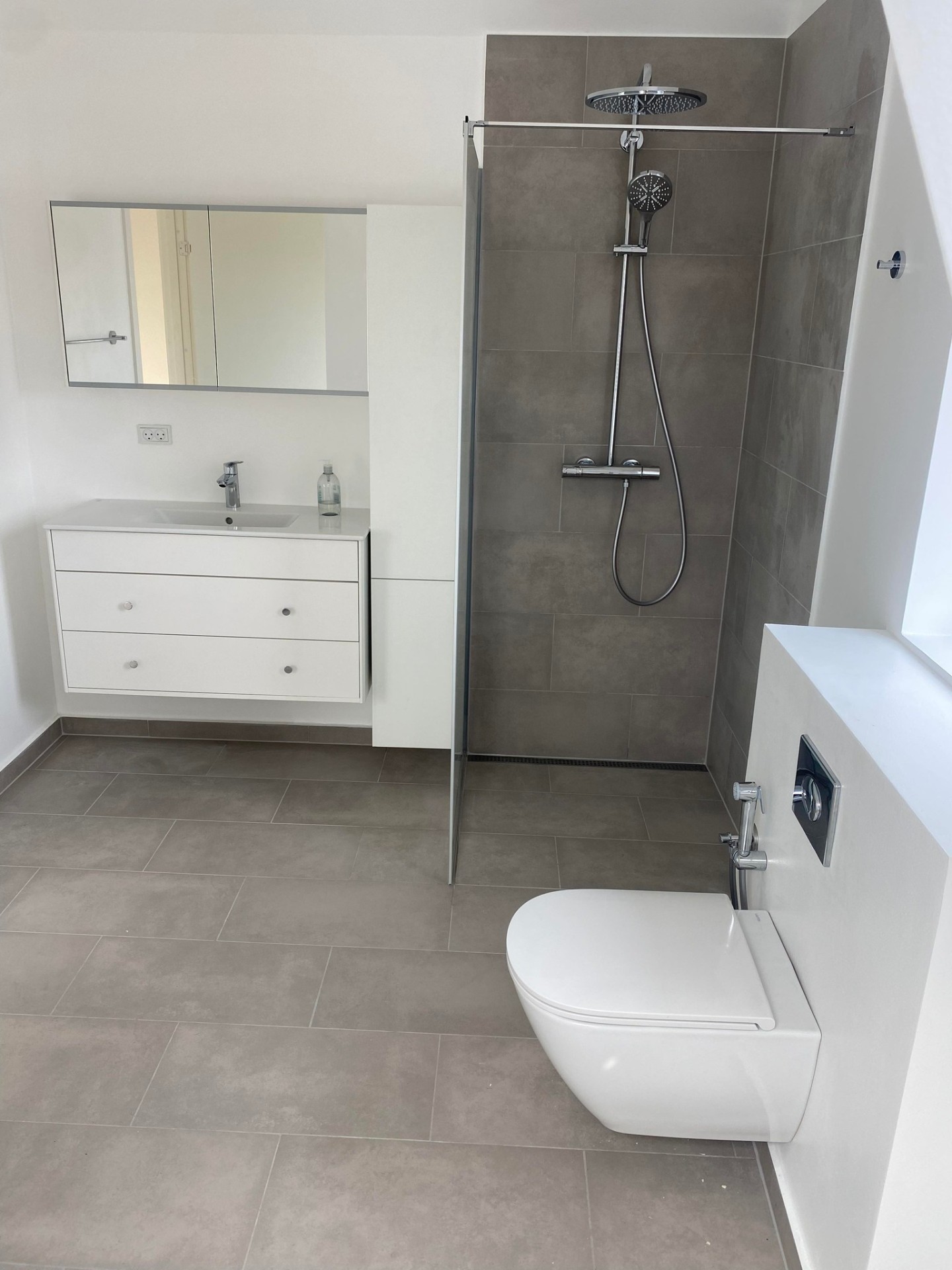 Moderne badeværelse med walk-in bruser og betonlook-fliser